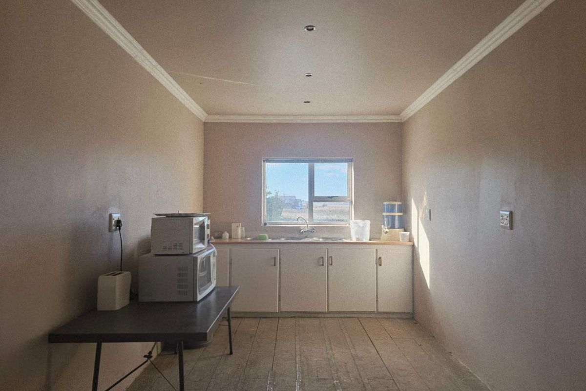 A basic kitchen area featuring simple cabinetry, a stainless steel sink, and recessed ceiling lighting, providing a functional workspace.