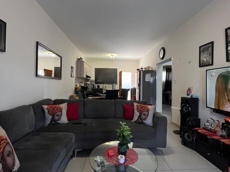 An open-plan living area featuring tiled flooring and a connected kitchen space, providing a functional layout for daily living.