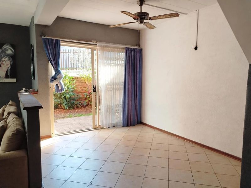 Living area featuring tiled flooring, a ceiling fan, and a sliding glass door providing direct access to the rear garden.