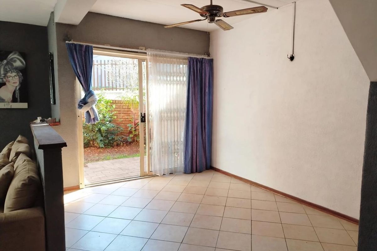 Living area featuring tiled flooring, a ceiling fan, and a sliding glass door providing direct access to the rear garden.