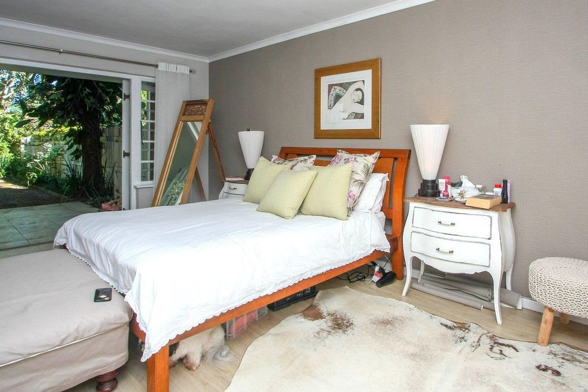 A well-lit bedroom featuring laminate flooring and direct access to a private garden through glass french doors.