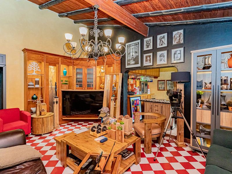 A living room featuring exposed timber ceiling beams, built-in wooden cabinetry, and distinctive red and white checkered tile flooring.