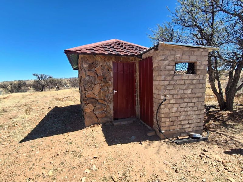 A small detached utility structure featuring stone and brick construction with a tiled roof, suitable for storage or outdoor service requirements.