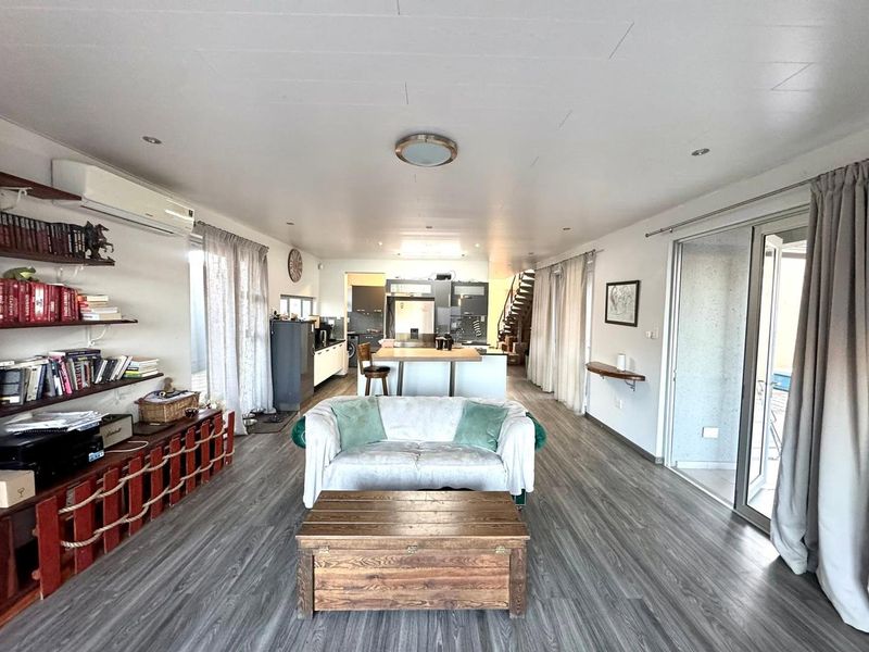 Spacious open-plan living area featuring modern laminate flooring, recessed lighting, and a functional kitchen with a central island and integrated cabinetry.