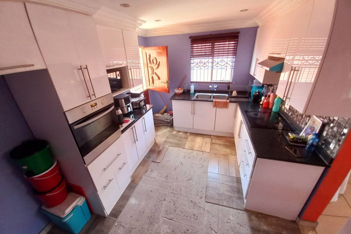 A functional kitchen featuring white cabinetry, dark countertops, a built-in oven, and a double sink with a window view.