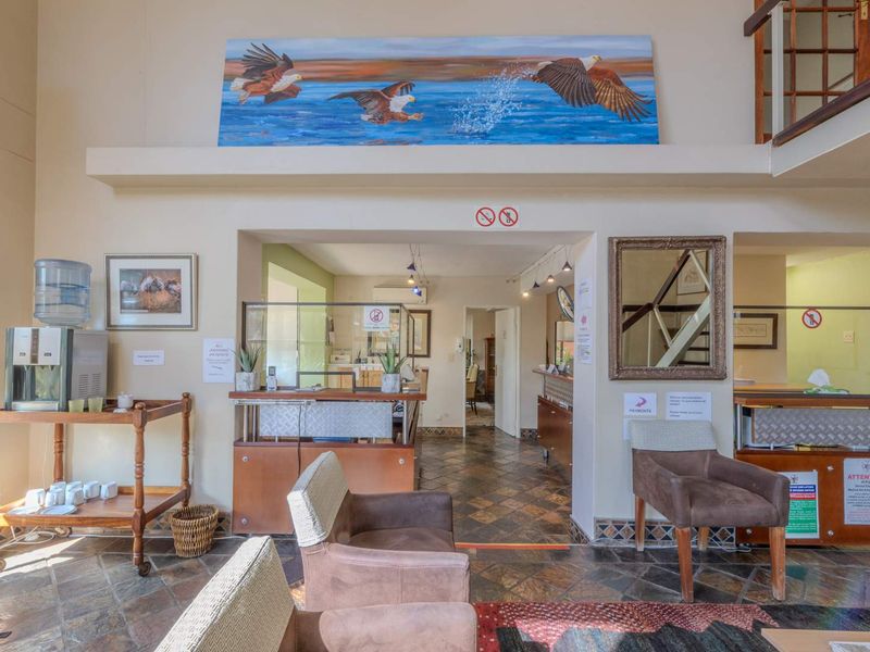 A spacious reception area featuring tiled flooring, a built-in service counter with glass partitions, and an open staircase leading to the upper level.