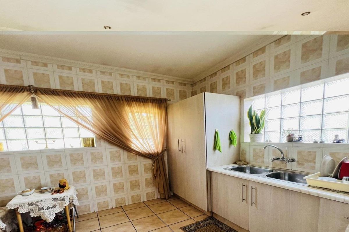 A functional kitchen featuring light-toned cabinetry, a double-basin sink, and glass block windows that provide natural light.