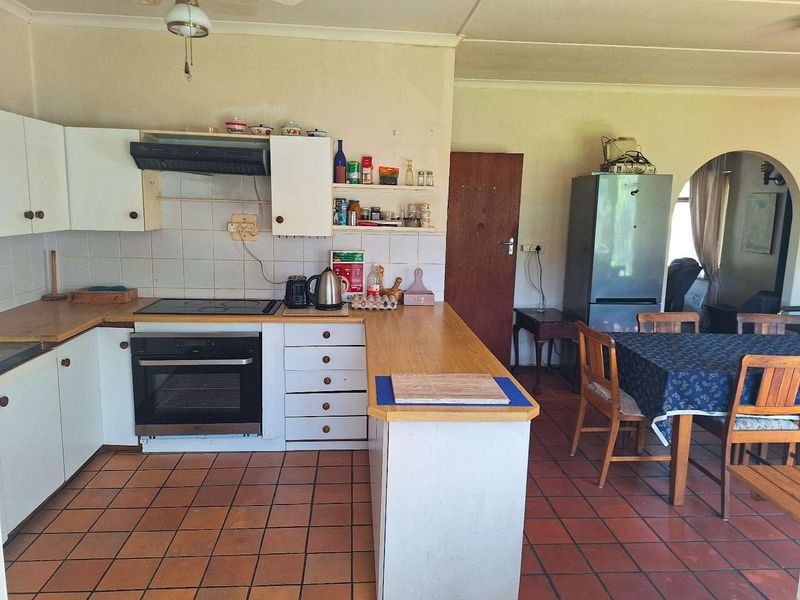 Open-plan kitchen featuring built-in oven, electric hob, extractor fan, and tiled flooring, offering a functional layout with potential for modern updates.