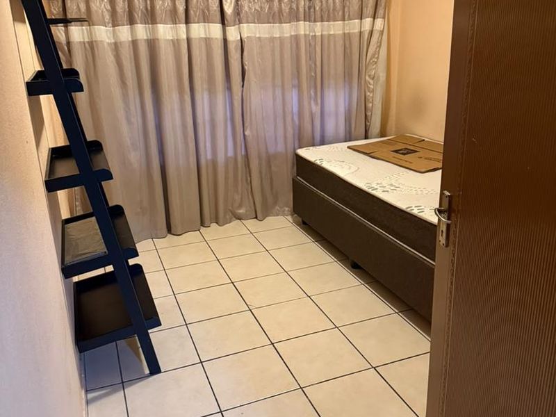 A compact bedroom featuring tiled flooring and a curtain rod, providing a functional space ready for personalization.