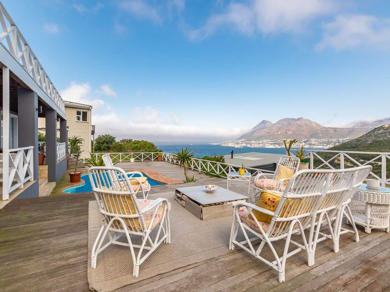 Spacious outdoor wooden deck featuring a swimming pool and panoramic coastal and mountain views, perfect for entertaining.