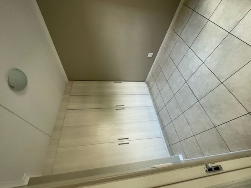 A clean, empty bedroom featuring neutral tiled flooring and built-in cupboards, offering a versatile space ready for personalization.