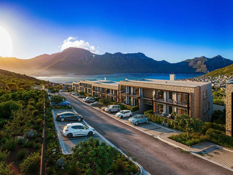 Aerial view of a modern apartment complex featuring stone-clad facades, private balconies, and landscaped grounds with mountain and coastal views.