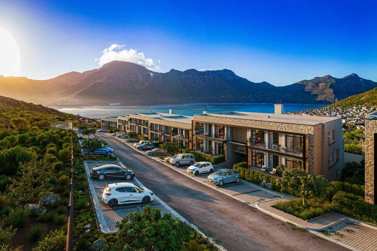 Aerial view of a modern apartment complex featuring stone-clad facades, private balconies, and landscaped grounds with mountain and coastal views.