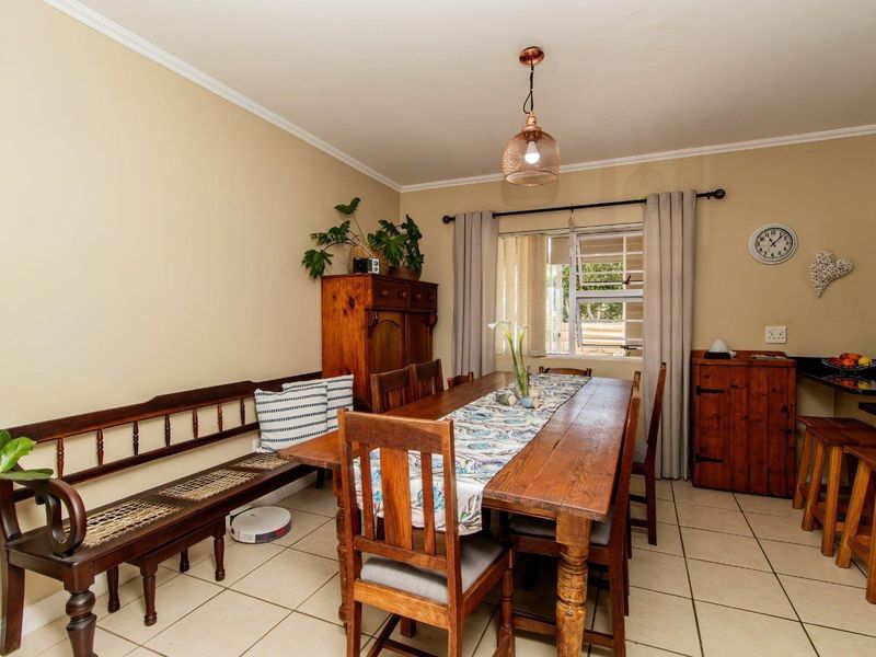 A functional dining area featuring tiled flooring, a central pendant light, and a breakfast bar counter with granite surfaces.