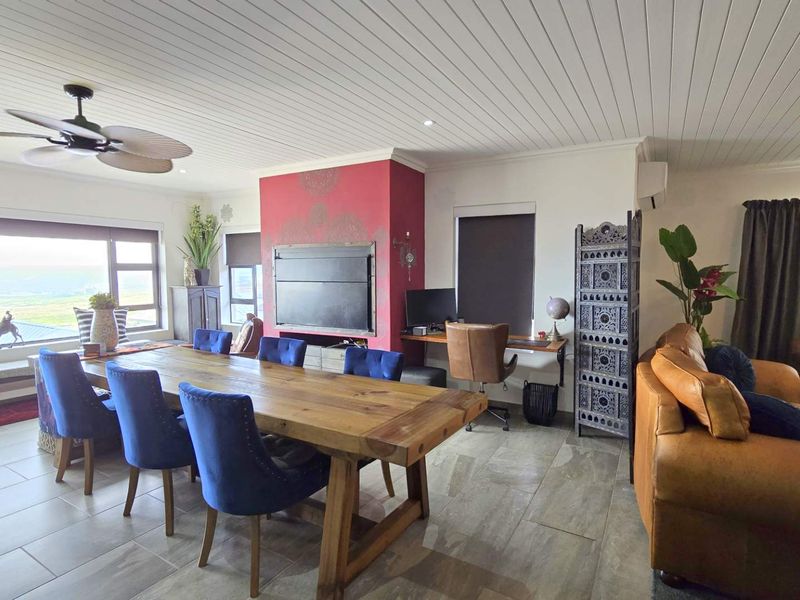 Spacious open-plan living and dining area featuring a built-in fireplace, tiled flooring, and a tongue and groove ceiling with a ceiling fan.
