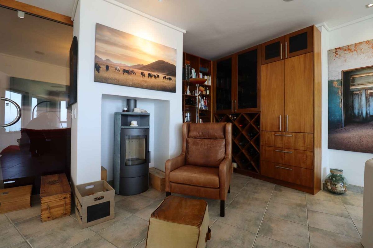 A cozy living area featuring a modern freestanding fireplace, custom built-in wooden cabinetry with integrated wine storage, and durable tiled flooring.