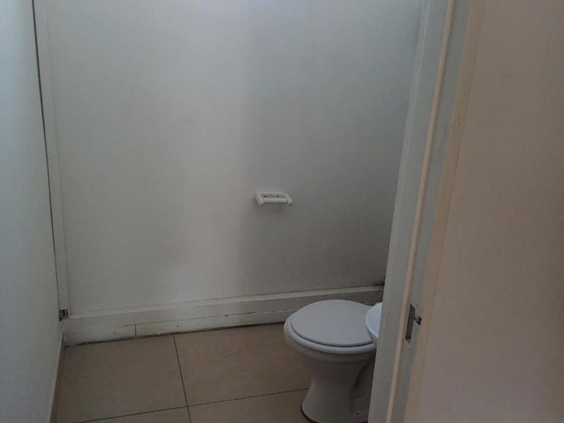 A compact, functional bathroom featuring tiled flooring, a standard toilet, and a small window for natural light.