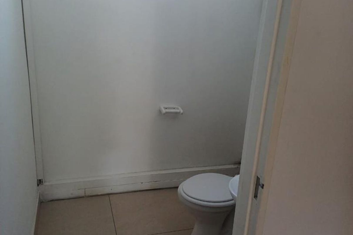 A compact, functional bathroom featuring tiled flooring, a standard toilet, and a small window for natural light.