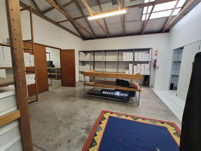 Functional office or storage space featuring exposed timber roof trusses, a skylight, and a combination of concrete and tiled flooring.