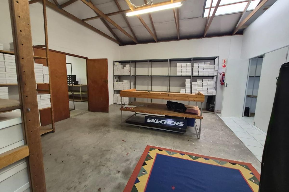 Functional office or storage space featuring exposed timber roof trusses, a skylight, and a combination of concrete and tiled flooring.