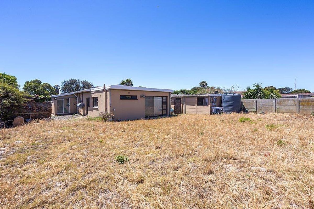 Rear view of the property featuring a large, dry garden area, precast boundary wall, and a water tank.