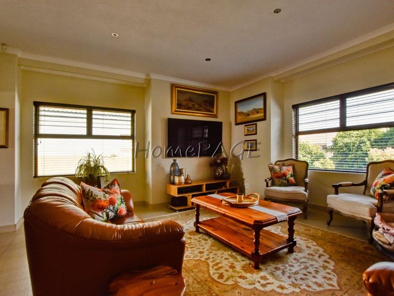 A comfortable living room featuring tiled flooring, recessed downlighting, and large windows with venetian blinds, providing a bright and functional space.