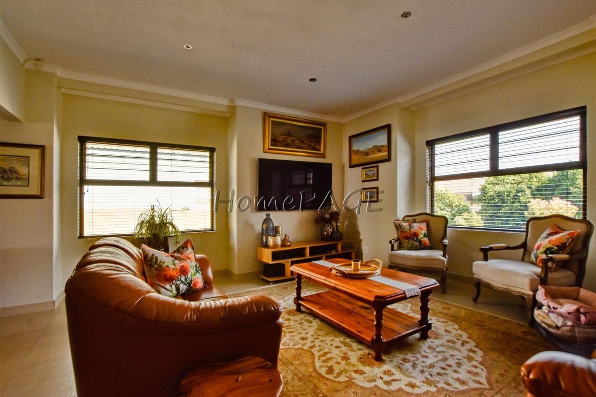 A comfortable living room featuring tiled flooring, recessed downlighting, and large windows with venetian blinds, providing a bright and functional space.