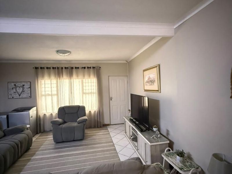 A comfortable living room featuring tiled flooring, neutral wall tones, and natural light through a window with curtains.