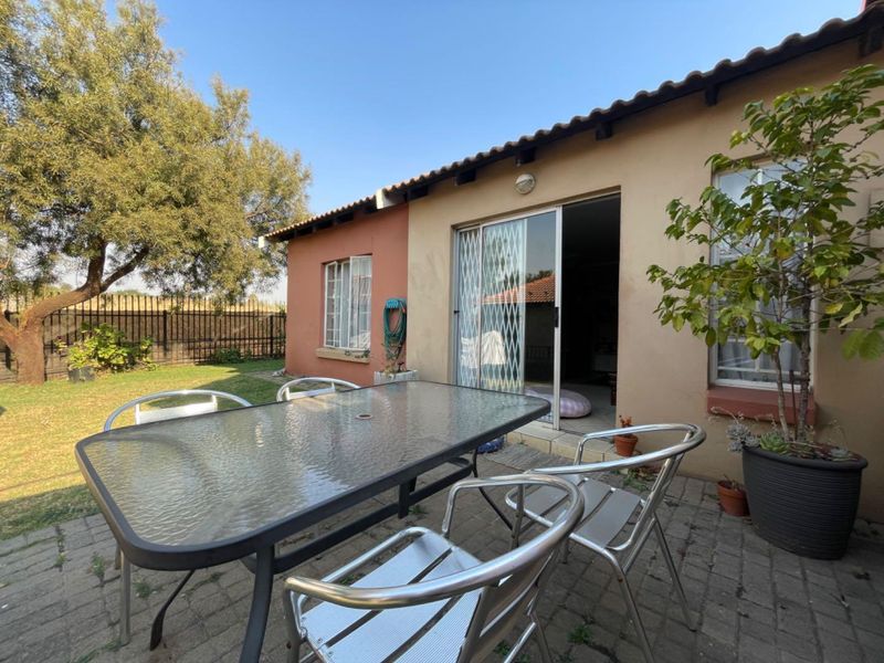 Rear exterior view of the property featuring a paved patio area, sliding glass door with security gate, and access to the garden.
