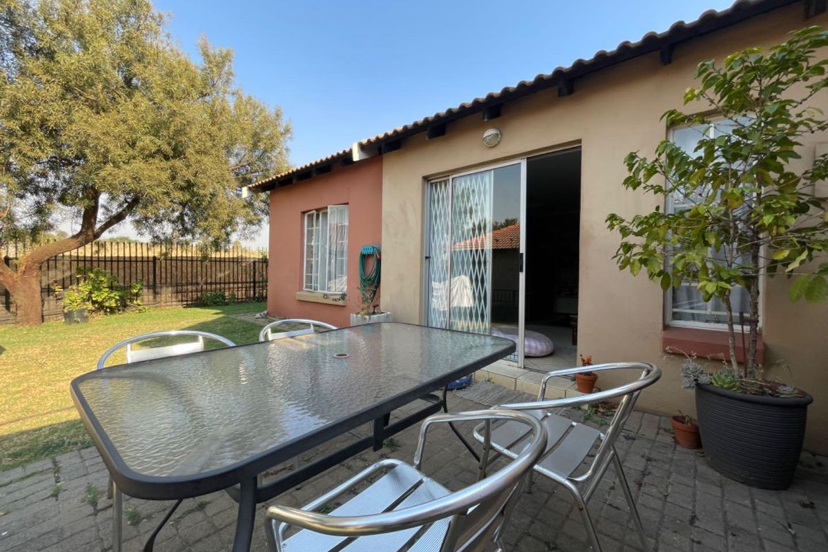 Rear exterior view of the property featuring a paved patio area, sliding glass door with security gate, and access to the garden.