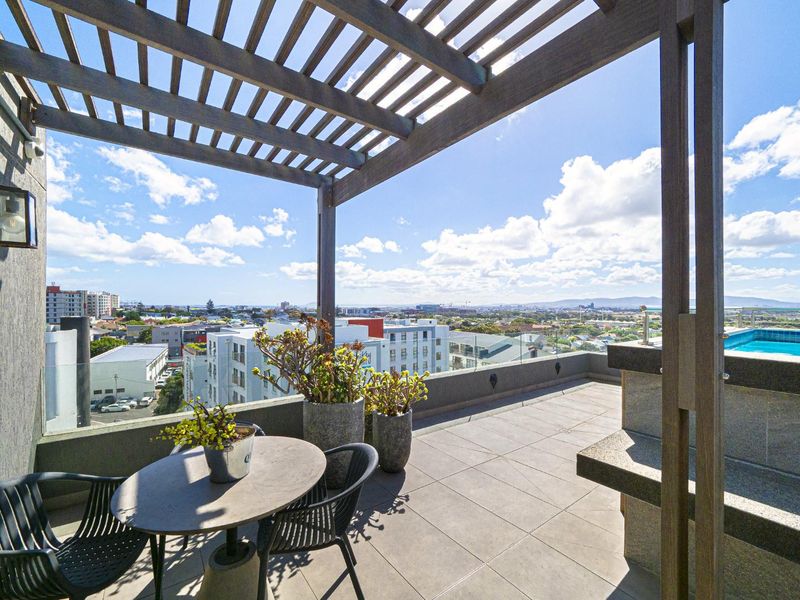 Spacious rooftop balcony featuring a timber pergola, glass balustrade, built-in stone counter, and a private plunge pool with panoramic city views.