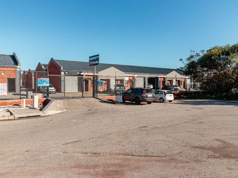 Front view of Moffett Park commercial property featuring brick facade, metal roofing, secure gated access, and paved parking area.