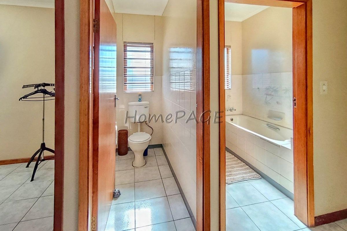 A functional bathroom layout featuring a separate toilet and a bathtub area with tiled flooring and wooden door frames.