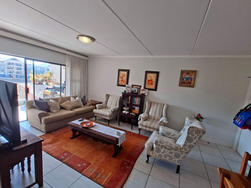 Spacious living room featuring tiled flooring and a large sliding glass door providing access to an outdoor balcony area.