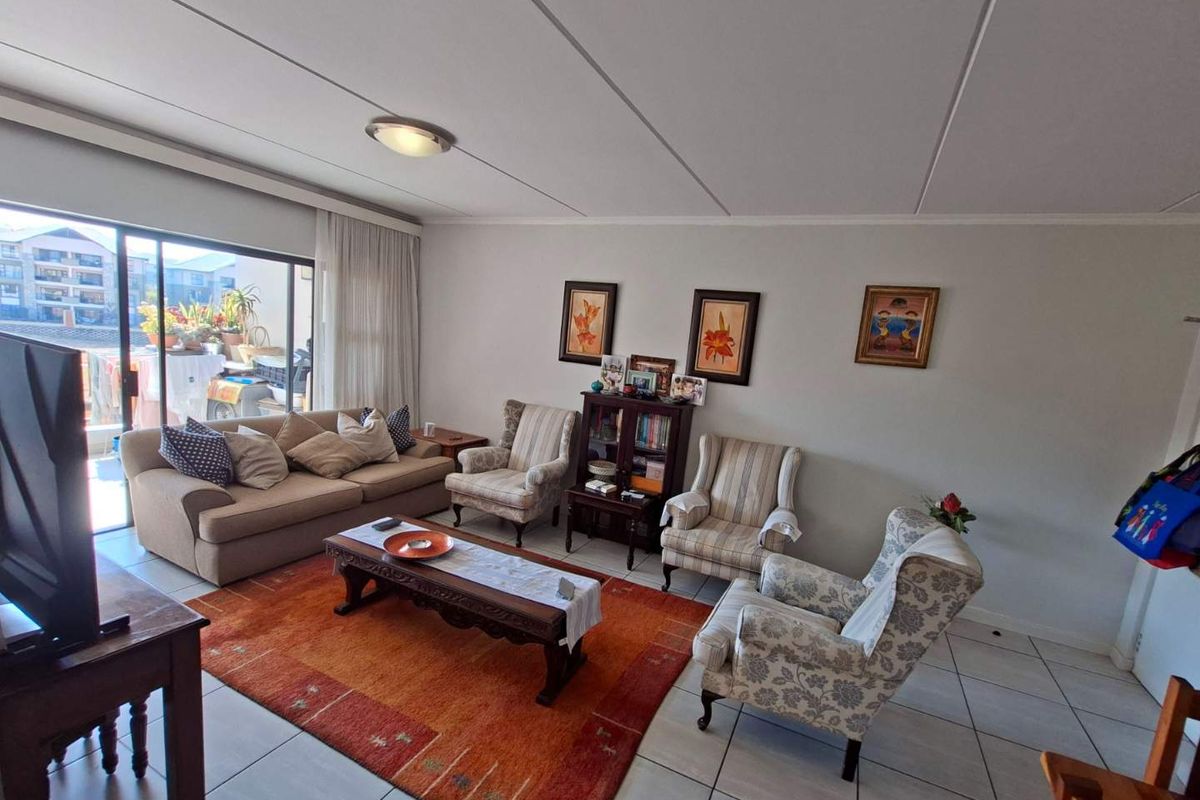 Spacious living room featuring tiled flooring and a large sliding glass door providing access to an outdoor balcony area.