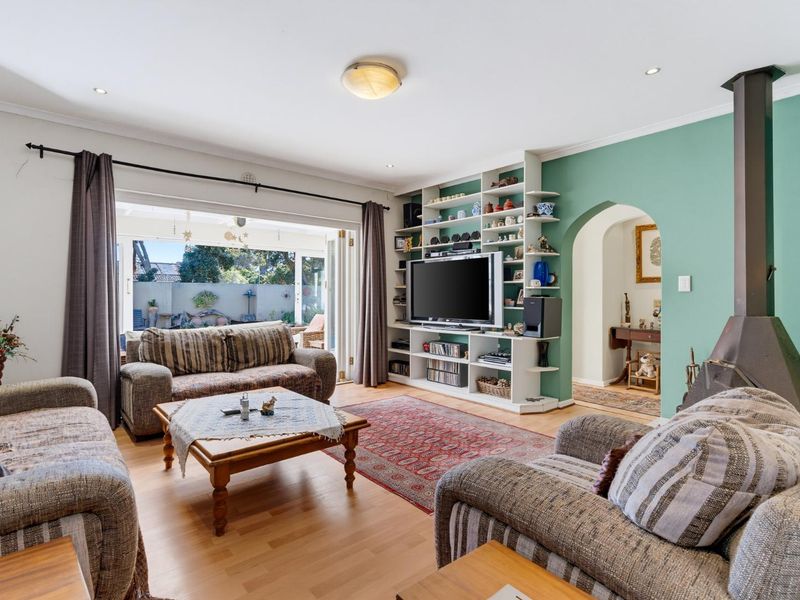 Spacious living room featuring a built-in shelving unit, a freestanding fireplace, and bi-fold doors opening to an outdoor area.