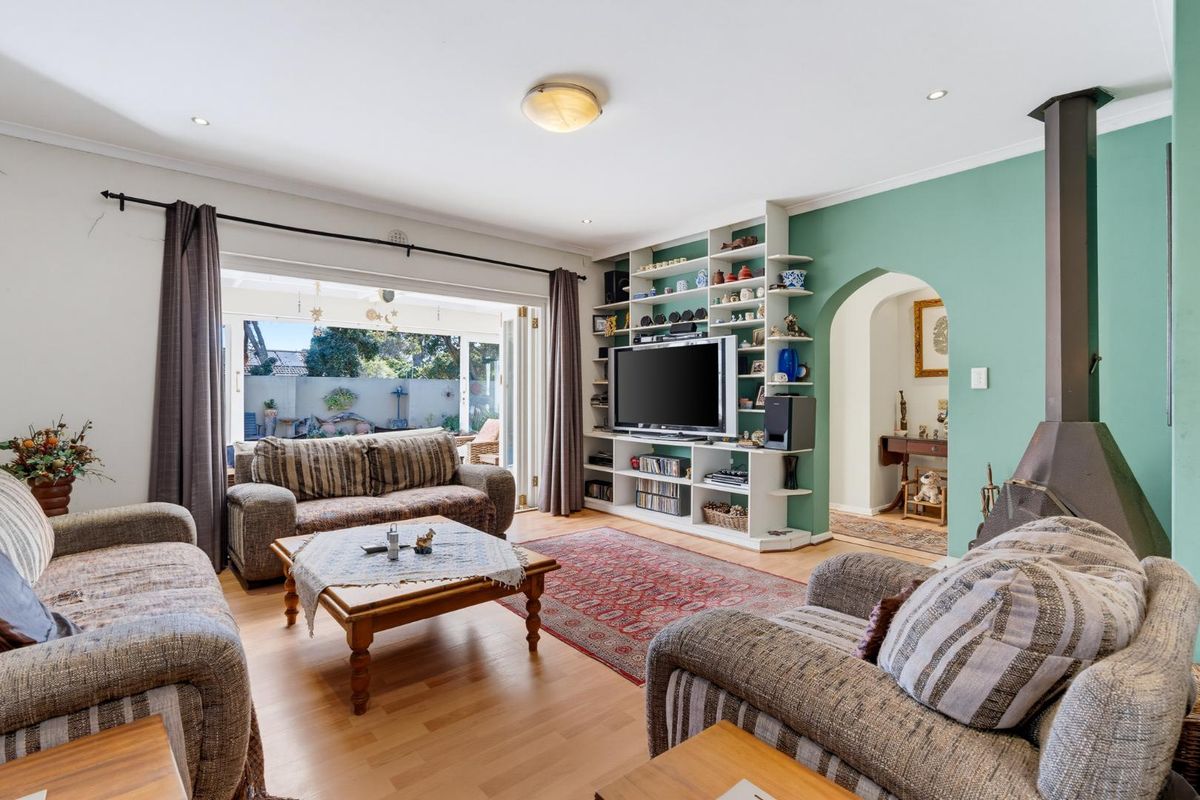 Spacious living room featuring a built-in shelving unit, a freestanding fireplace, and bi-fold doors opening to an outdoor area.