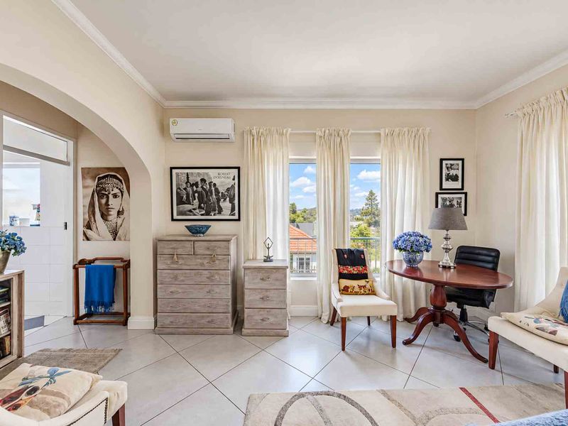 A bright living room featuring tiled flooring, a split-system air conditioner, and an arched entryway leading to an adjacent space.