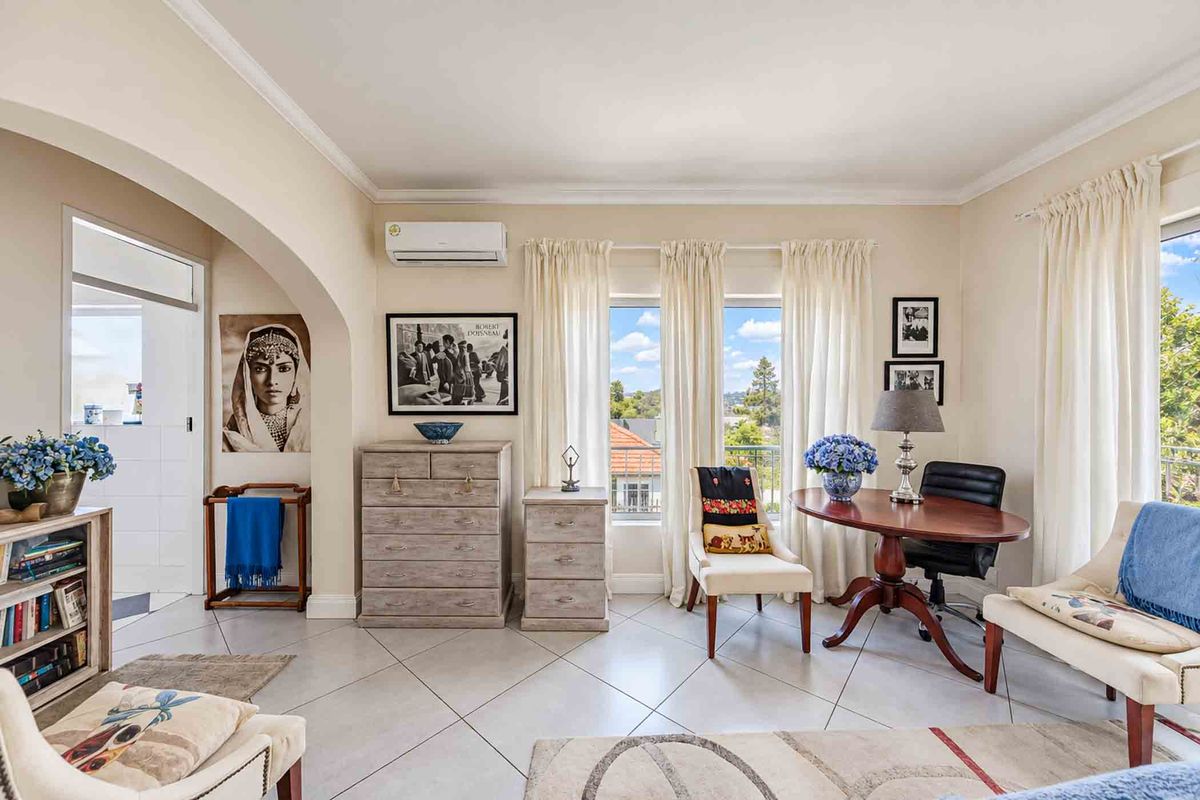 A bright living room featuring tiled flooring, a split-system air conditioner, and an arched entryway leading to an adjacent space.