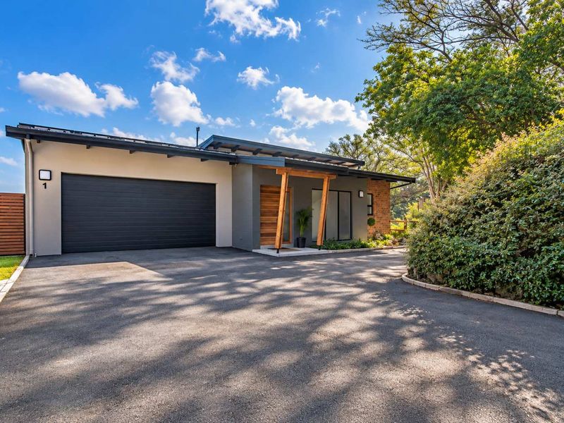 Modern townhouse exterior featuring a sleek asphalt driveway, automated garage, and a striking timber entrance pergola with contemporary architectural finishes.