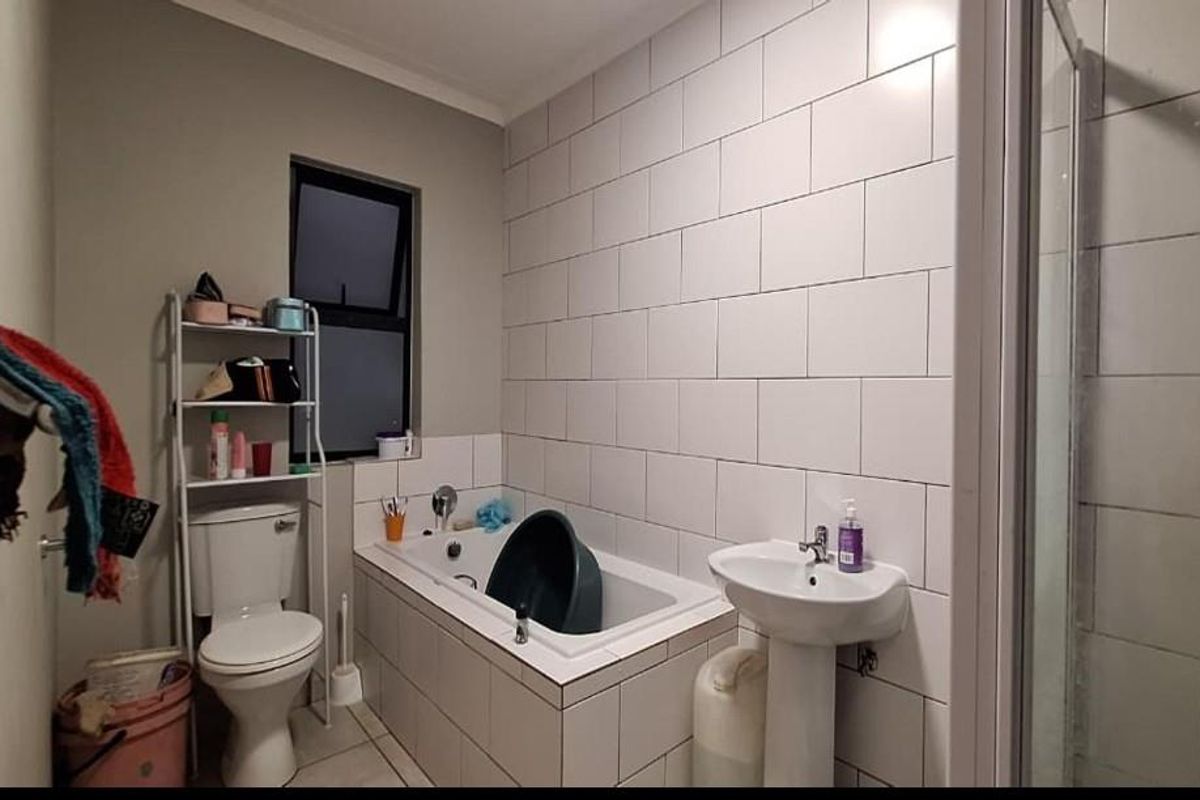 A functional bathroom featuring a white bathtub, pedestal basin, and a separate shower enclosure with tiled walls.