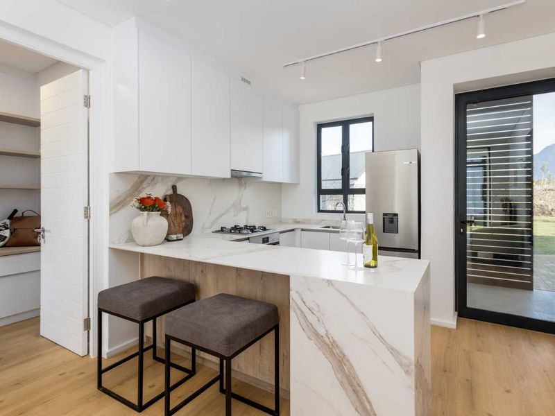 Modern kitchen featuring marble-look stone countertops, breakfast bar, gas hob, integrated cabinetry, and direct access to an outdoor area.