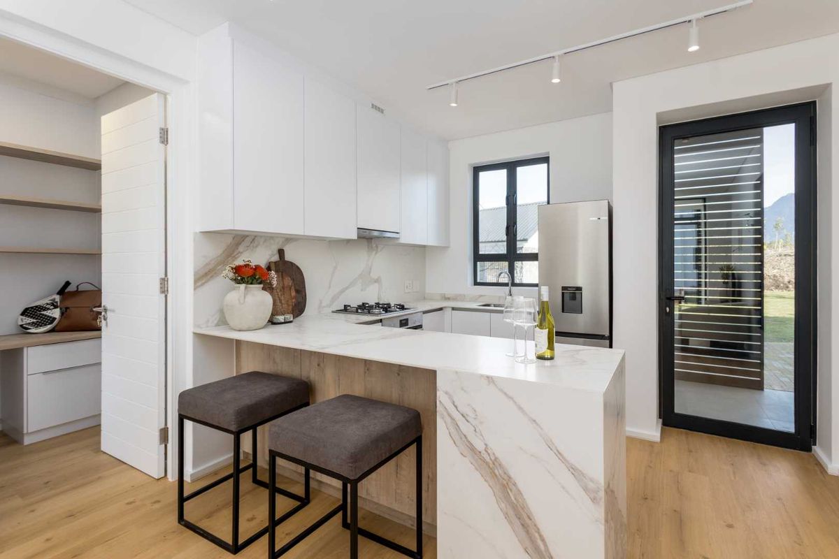 Modern kitchen featuring marble-look stone countertops, breakfast bar, gas hob, integrated cabinetry, and direct access to an outdoor area.