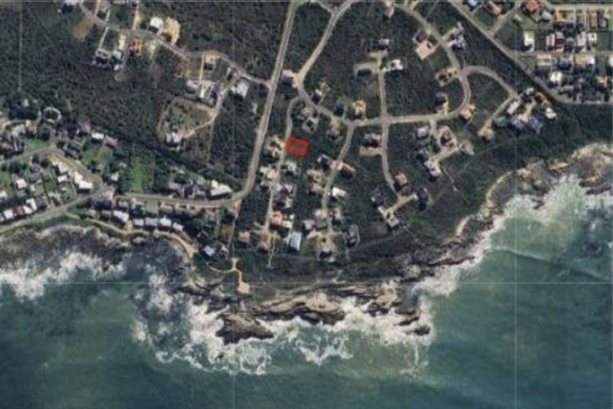 An aerial view of a residential plot located in a coastal neighborhood, highlighting its proximity to the ocean and surrounding infrastructure.