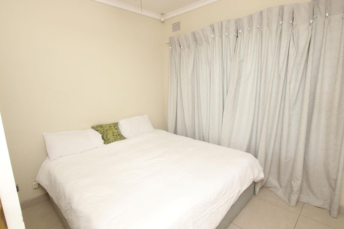 A bedroom featuring tiled flooring, neutral wall finishes, and floor-to-ceiling curtains covering the window area.