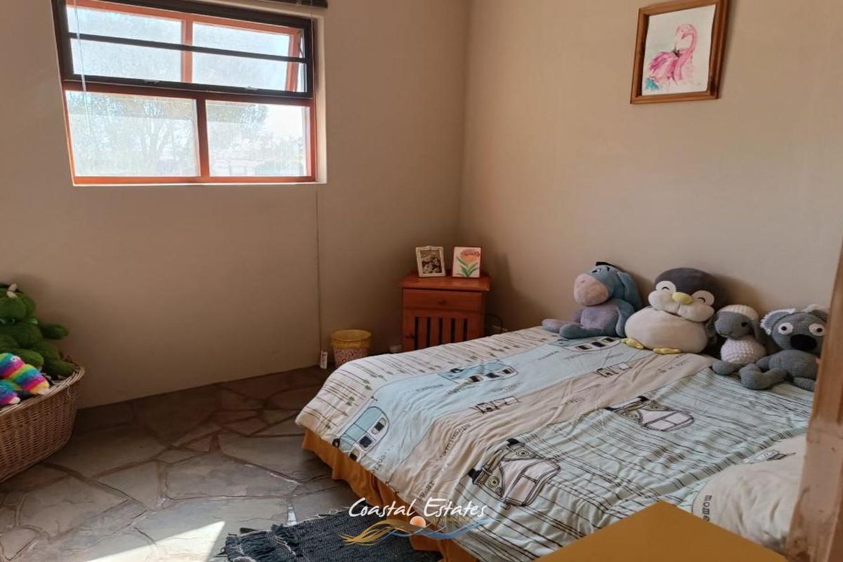 A bedroom featuring natural stone flooring and a large window, providing a functional and comfortable living space.