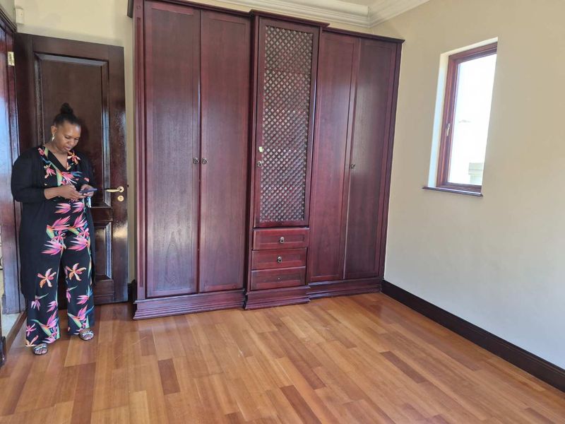 A bedroom featuring built-in dark wood cabinetry, laminate flooring, and a window, providing a clean and functional space.
