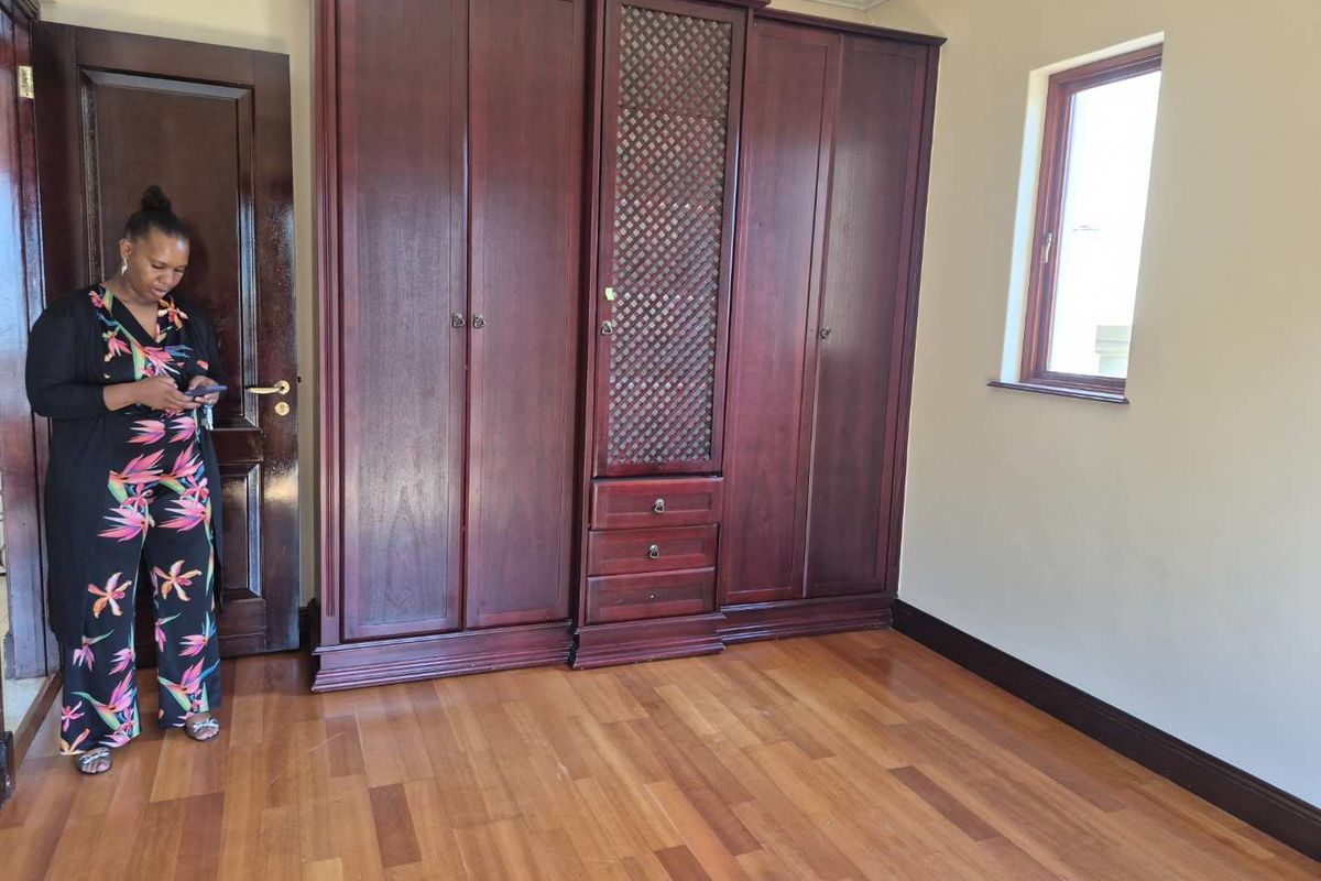 A bedroom featuring built-in dark wood cabinetry, laminate flooring, and a window, providing a clean and functional space.