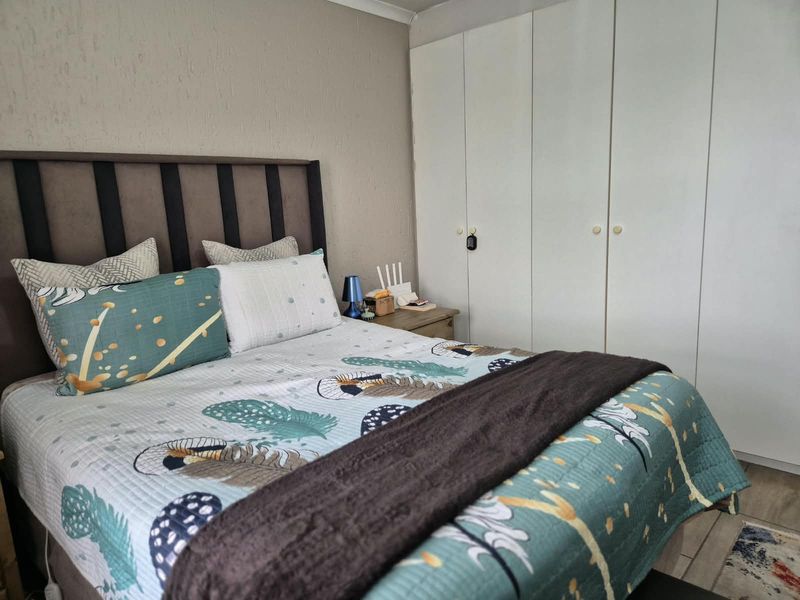A bedroom featuring built-in cupboards and laminate flooring, providing functional storage and a neutral base for interior design.