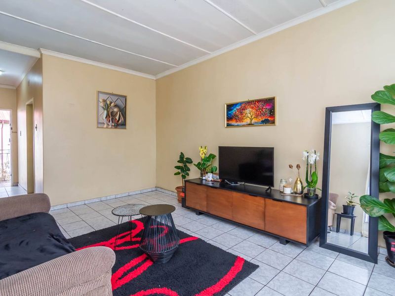 A living room featuring tiled flooring and a panelled ceiling, providing a functional and neutral space for relaxation.